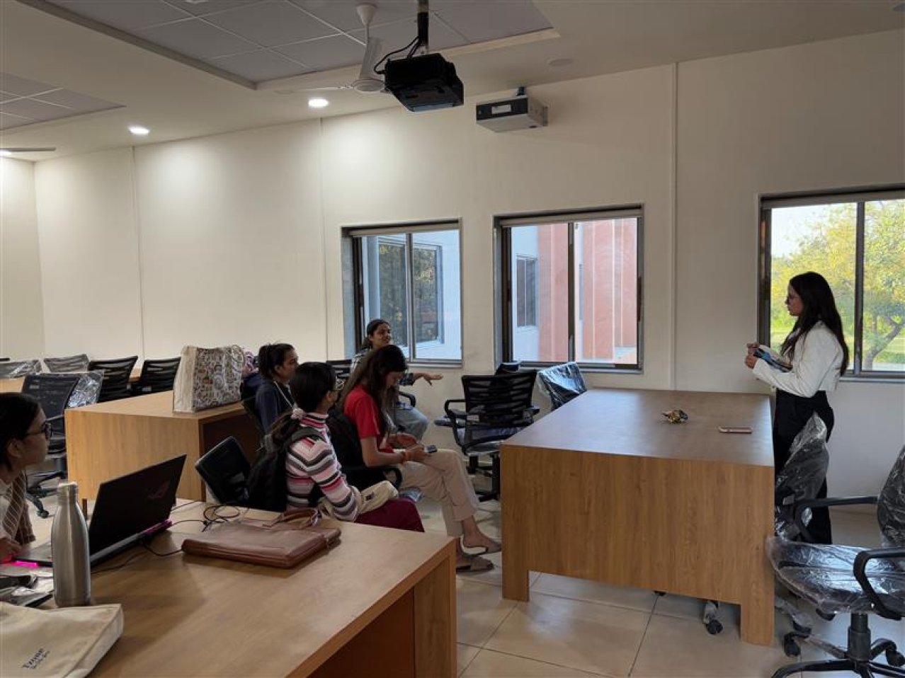 The designer standing at the front of a classroom, talking with a group of seated students during an interview session.